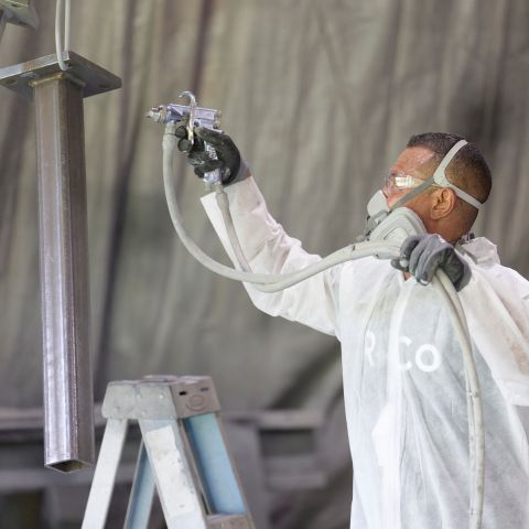 Renfrow+Co team member in protective gear painting a metal structure highlighting their comprehensive fabrication and finishing process